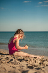 Fototapeta na wymiar Cute little girl playing in the sand on the sea beach