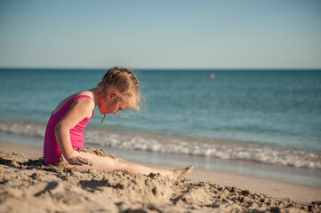 Cute little girl playing in the sand on the sea beach