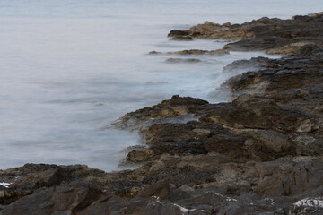 Fototapeta na wymiar A photo of the blurry sea waves on the rocky shore of the Adriatic Sea
