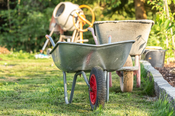 A wheelbarrow in front of a building lot at a garden