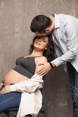 Beautiful happy couple is expecting a baby. A married couple expecting a child in a photo studio.