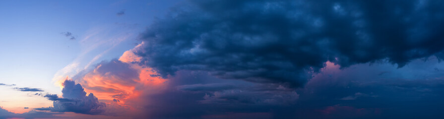 Naklejka na ściany i meble Dramatic sunset sky with dark stormy clouds.