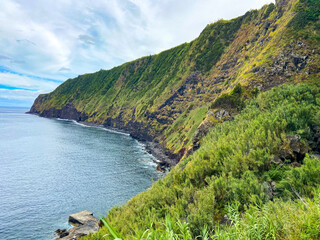 Green coastal cliffs touching the blue ocean in Sao Miguel island, Azores.