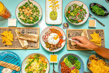 set of salads from around the world, wrap with corn nachos, salmon poke bowl, fried meat and cheese sauce, wakame seaweed salad, spinach and avocado salad