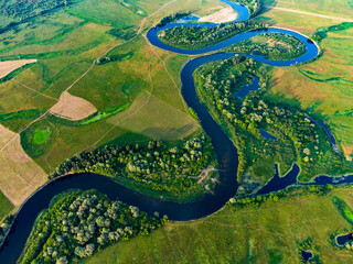 Aerial view of curve blue river with trees on the fields