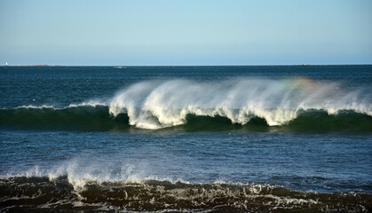 Rainbow in the crashing surf, with a distant lighthouse, at easton’s Beach near Newport, Rhode Island 