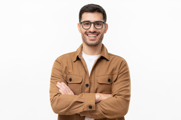 Portrait of young happy laughing man wearing brown shirt and eyeglasses, holding arms crossed, isolated on gray background