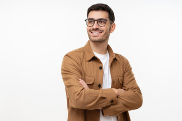 Confident young man looking away, standing with crossed arms isolated on gray