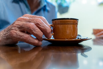 Closeup view of the old hands of an elder man taking a cup if coffee 