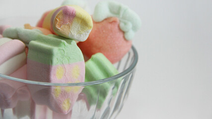 Marshmallow in a glass vase on a white background. Marshmallows in the form of different figures in a vase.Candys