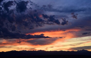 dramatic sunset and virga clouds over long's peak and the front range of the colorado rocky mountains, as seen from broomfield, colorado