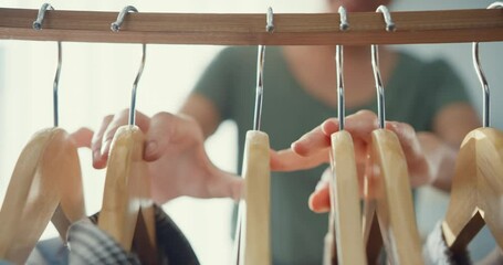 Closeup attractive Asia lady choosing clothes on clothes rack dressing looking herself in mirror in living room at house. Girl think what to wear casual shirt. Lifestyle women relax at home concept.
