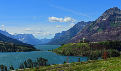 Naklejka na ściany i meble the spectacular view on a sunny day across turquoise-colored waterton lakes to prince of wales hotel in waterton, alberta, canada, to the peaks of glacier national park, montana
