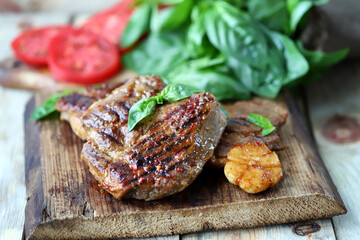 Grilled juicy steak on a wooden board. Steak house serving.