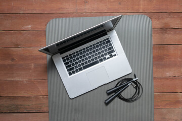 laptop and jump rope on yoga mat in gym studio