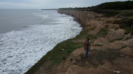 Young woman watching and walking front to ocean over huge cliff in South America