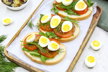 Fresh toast sandwiches with quail eggs, tomatoes and green herbs. Closeup. Top view. Copy space.