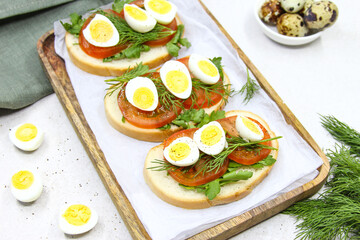 Fresh toast sandwiches with quail eggs, tomatoes and green herbs. Closeup. Top view. Copy space.