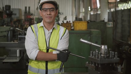 Portrait Asian engineer man worker wear safety goggles control lathe machine industrial manufacturing factory crossed arm smiling happily looking at camera, Heavy industry lathe worker man