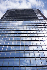 Blue sky and clouds are reflected on the outer wall window of a skyscraper