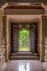 Traditional balinese handmade carved wooden door. Bali style furniture with ornament details. Old and vintage local style of architecture in Bali. Handmade details.