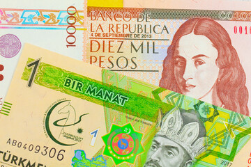A macro image of a brown ten thousand bank note from Colombia paired up with a green and yellow one manat note from Turkmenistan.  Shot close up in macro.