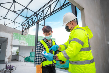 Coronavirus concept and the construction industry : Civil engineer supervisors measure temperature of construction workers at construction sites. fever test Measure temperature in construction site.