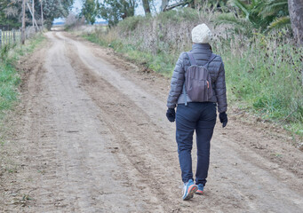 Mujer caminando en medio de un camino rural.