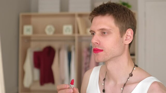 Young transgender transsexual gay man applying make-up red lip stick, LGBTQ Man in women's clothing wearing makeup. womanlike man with make up on face and woman clothes, looking fashion glamorous