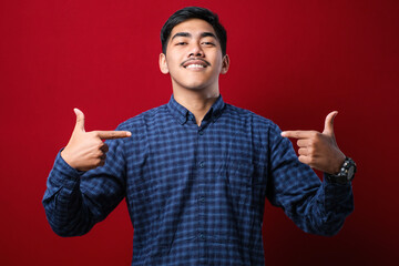 Young handsome man wearing casual shirt looking confident with smile on face, pointing oneself with...