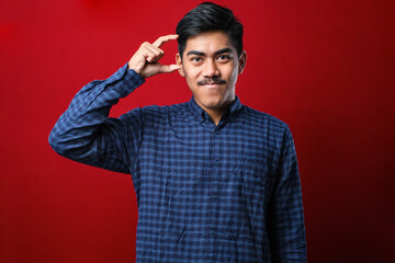 Naklejka premium Young handsome man wearing casual shirt smiling and confident gesturing with hand doing small size sign with fingers looking and the camera. measure concept.