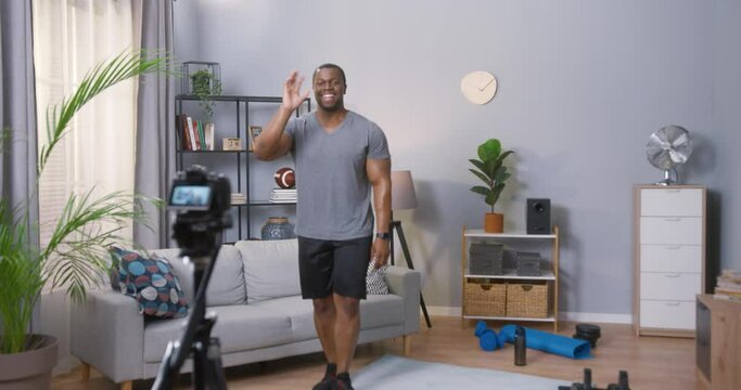 Young man blogger showing at his abdominal muscles while recording his daily video blog. Blogger using a camera mounted on a tripod to record her video about sport