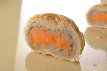 baked round crispy purple yam taro with sweet potato pumpkin sweet paste and egg yolk teochew mooncake on marble table lantern mid autumn festival chinese halal pastry product menu