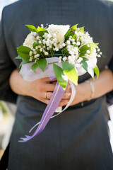 a beautiful bride in a white dress holds a bouquet of fresh flowers