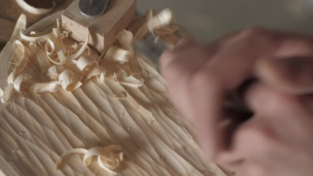 a craftsman processes a pine wood board with a chisel. artisan makes a tea tray. the art of woodworking. work with hand carpentry tools. woodworking sounds
