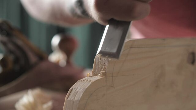 carpenter cuts off excess on a wooden board with a flat chisel. wood craftsman working with chisel. using hand carpentry tools