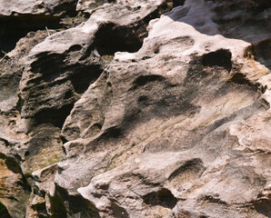 The uneven surface of a huge stone lit by the sun, close-up