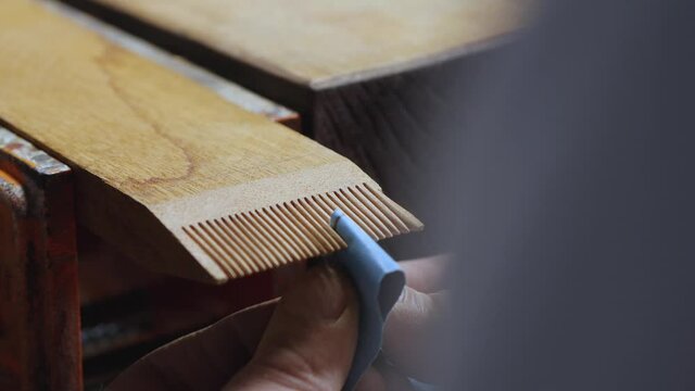 close-up. joiner grinds teeth on a wooden comb with sanding paper. making a wooden beard comb. work with hand carpentry tools