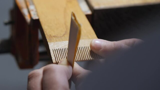wood craftsman grinds teeth on a wooden comb with sanding paper. making a wooden beard comb. work with hand carpentry tools