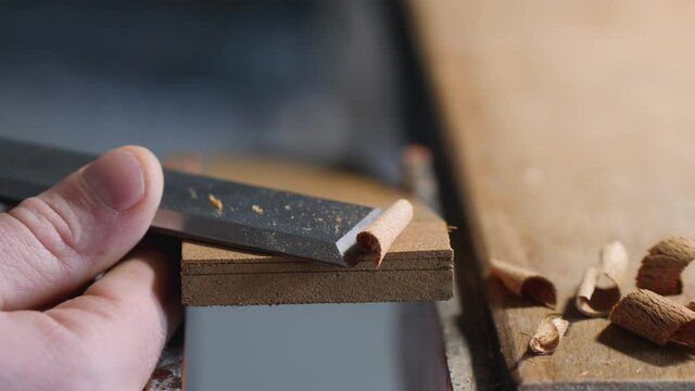 chisel work. craftsman carpenter removes excess thickness from a wooden board with a flat chisel. making wooden beard combs