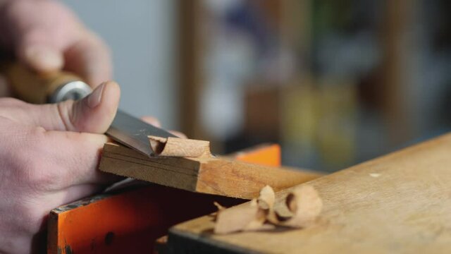 craftsman carpenter removes excess thickness from a wooden board with a flat chisel. making wooden beard combs. chisel work