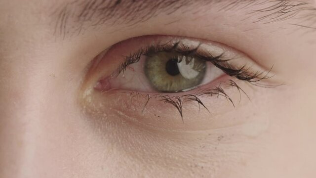 Human eye close up. The green eye is painted with ink. Mascara spreads on the face.