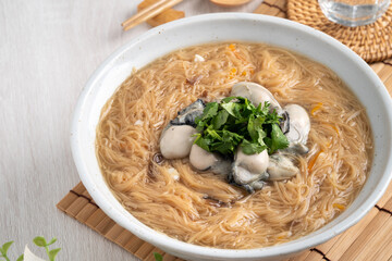 Delicious oyster vermicelli in a bowl on wooden table background.