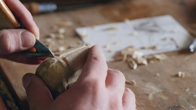 a woodcarver carves a helmet of a robot or a knight with a knife. wood carving in a carpentry workshop. the art of woodcarving and woodworking. the sound of hand carpentry tools