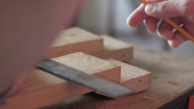a carpenter marks a wooden board with a try Square. Square frame is used to mark a wooden board with a pencil. Make a mark with a pencil.