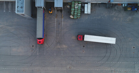 Aerial Shot of Industrial Warehouse Loading Dock where Many Truck with Semi Trailers Load...
