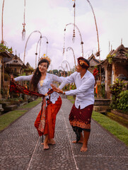 Multicultural couple dancing traditional Balinese dance. Happy couple spending time together. Caucasian wife and Balinese husband. Romantic relationship. Penglipuran, Bali