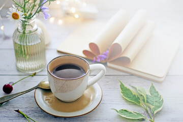 Coffee time. A cup of coffee on the table surrounded by books, flowers, berries. Romantic background with coffee cup, copy space
