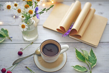 Coffee time. A cup of coffee on the table surrounded by books, flowers, berries. Romantic background with coffee cup, copy space