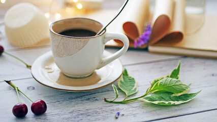Coffee time. A cup of coffee on the table surrounded by books, flowers, berries. Romantic background with coffee cup, copy space